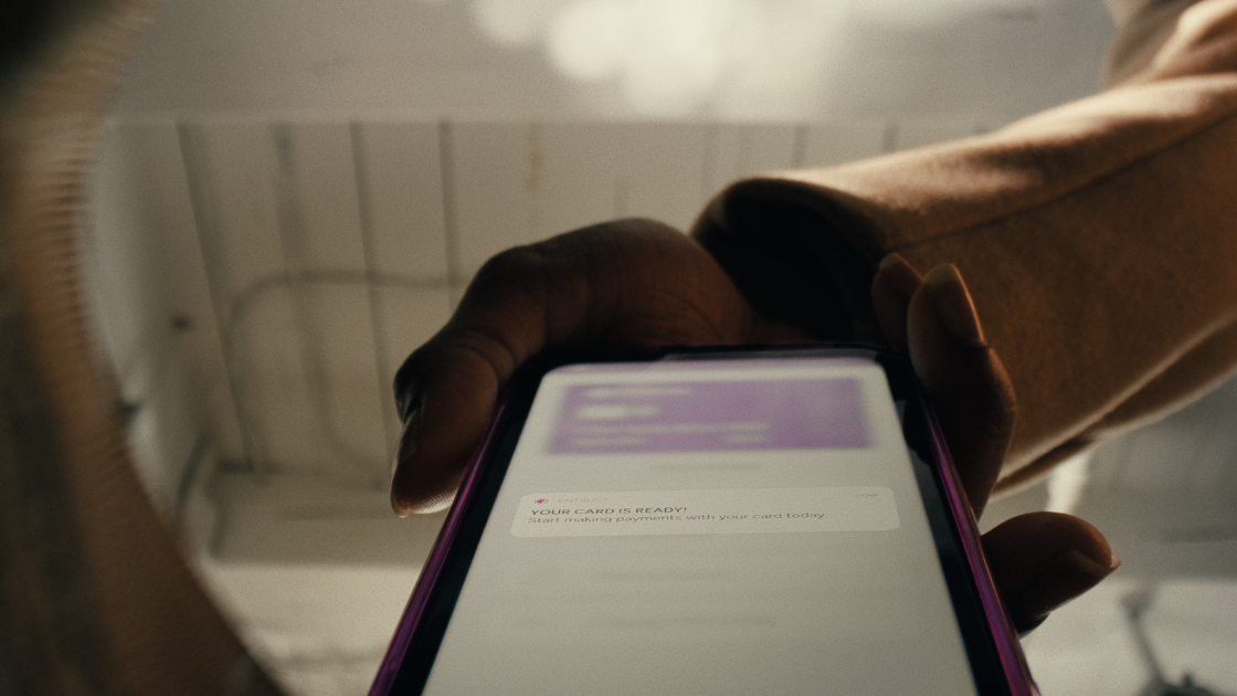 A tightly framed shot captures a real-time card activation alert, using moody lighting to dramatize mobile-first banking.