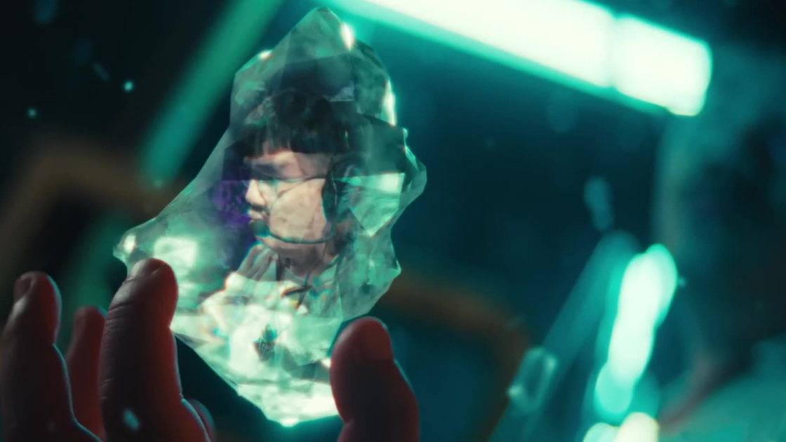A glowing, angular crystal is held delicately between fingers, revealing the face of a focused esports player inside. A sci-fi visual metaphor for captured skill, memory, or a fragment of gameplay frozen in time.