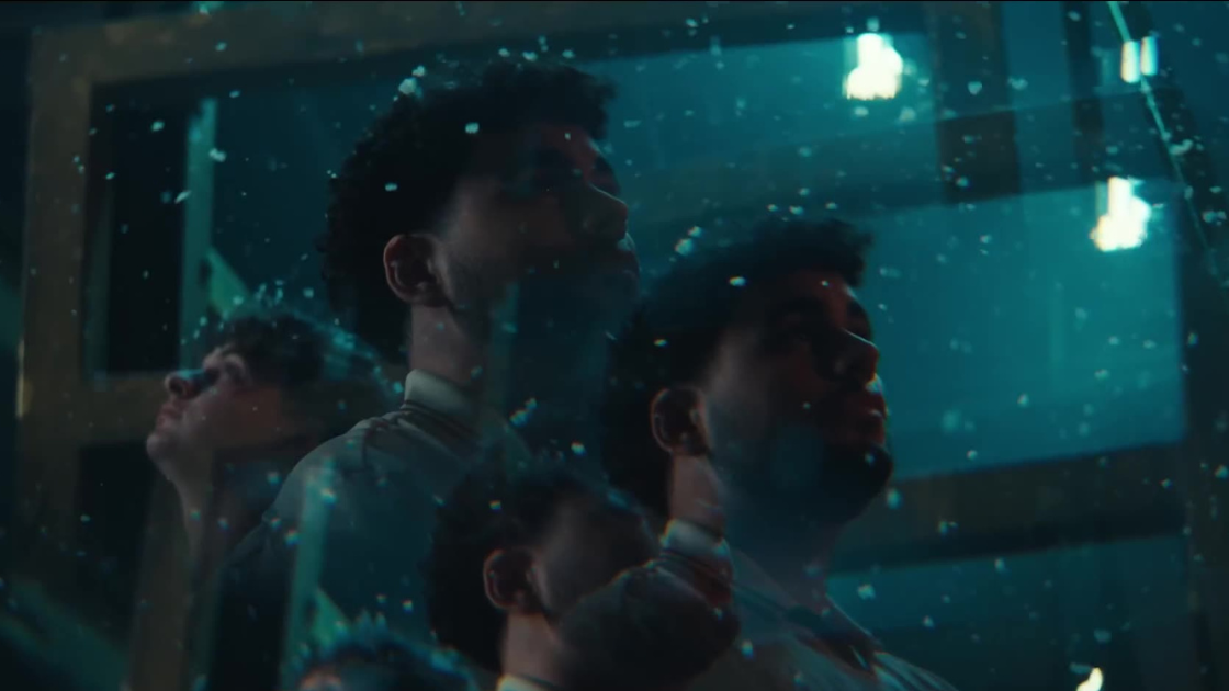 A layered, kaleidoscopic shot of a team, reflected multiple times through cracked glass. The image feels fractured yet unified, embodying the layered tension of team dynamics and shared purpose.