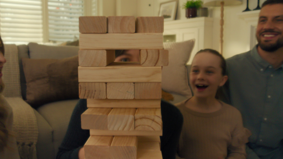 A playful family moment with a child peeking through a Jenga tower, surrounded by cozy furnishings and grounded by a neutral-toned rug.