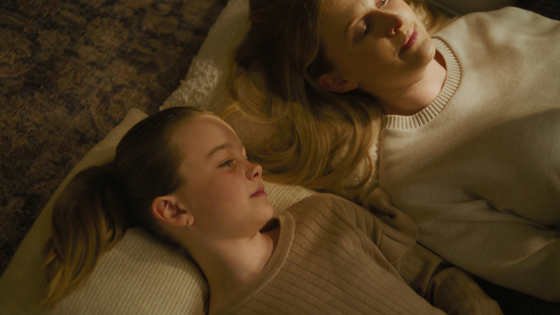 A tender moment as a mother and daughter lie side by side on a cozy Tumble rug, bathed in soft golden light that highlights the calm and comfort of home.